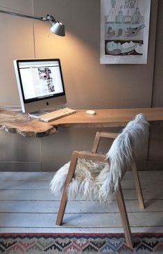 a desk with a computer on it and a furry chair in front of the monitor