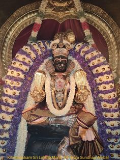 an idol is displayed in front of a large wall with purple and gold decorations on it