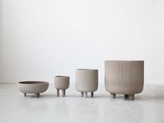 three white vases sitting on top of each other in front of a white wall