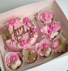 pink and gold decorated cupcakes in a box