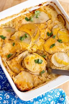 a casserole dish with potatoes and parsley in it on a blue napkin