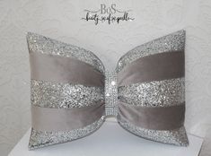 a decorative pillow with silver sequins on the front and grey ribbon at the back