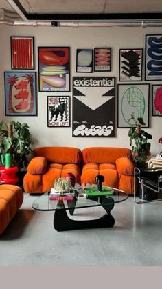 a living room filled with orange couches and pictures on the wall above each sofa