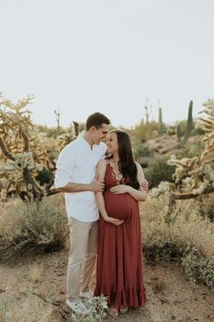 a pregnant couple standing in front of cacti