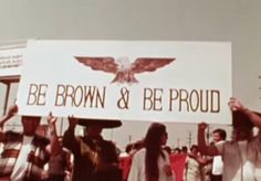 a group of people holding up a sign that says be brown & be proud