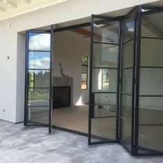 an open glass door on the outside of a house with a fireplace in the middle