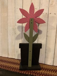 a paper flower sitting on top of a potted plant in front of a wooden wall