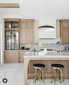 a kitchen with two stools in front of the island and an overhead light above it