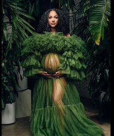 a woman in a green dress standing next to plants