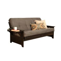 a brown futon sofa with pillows and a cup on the table next to it