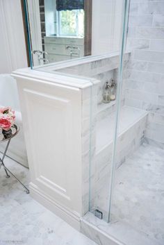 a bath room with a stand up shower next to a sink and a mirror on the wall