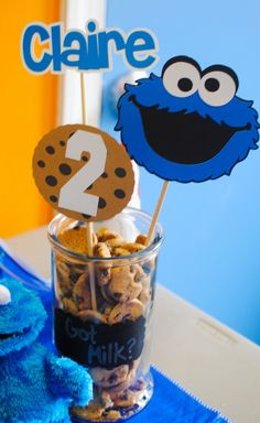 the cookie monster is sitting next to some cookies in a cup with a number two on it