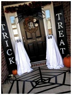 two halloween decorations on the front door of a house with ghost faces and black spider web