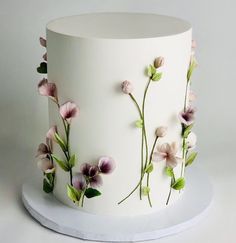 a white cake decorated with pink flowers and green leaves