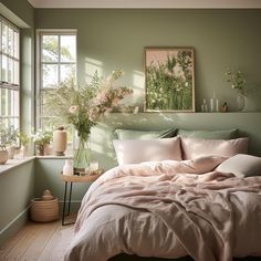 a bedroom with green walls, white bedding and flowers in vases on the window sill