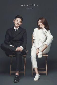 a man and woman sitting next to each other on chairs in front of a gray background