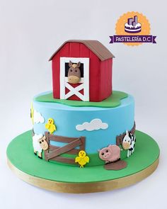 a cake with farm animals on it and a red barn in the background that says pastellila d'ac