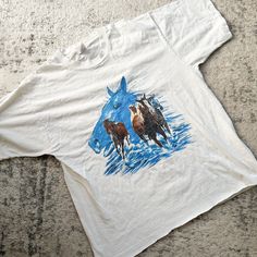 CURRENTLY OUT OF TOWN / THIS WILL SHIP AFTER OCTOBER 19TH. ENJOY 30% OFF - DISCOUNT ALREADY TAKEN!  Vintage white cotton tshirt with screen printed horses on front. Single stitched.  Era✦ 1980s Material✦ 100% cotton Closure✦ pullover  Condition✦ few age spot, minor cracking of the graphic and cut off hem. (cleaned & comes from a smoke-free home) ✂Measurements: Please do not go by its original tag size. Always go by the measurements listed below!!taken flat and doubled. Fits like women's L.  bust Age Spot, Horse Shirt, Horse T Shirts, Vintage Horse, Dress Form, Mens Graphic Tee, Cut Off, Womens Clothing Tops, White Vintage