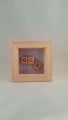 two scrabbles in a wooden frame with the word oclp spelled out