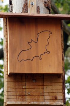 a wooden bird house with a bat drawn on it