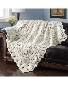 a white crocheted blanket sitting on top of a couch