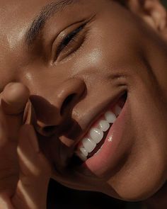 a woman smiling and holding her hand to her face