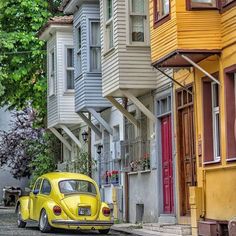 a yellow vw bug parked in front of some houses on the side of a street