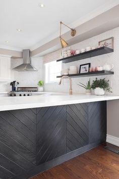 a kitchen with white counter tops and black wood paneling on the wall, along with open shelving