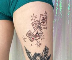 a woman's leg with tattoos on it and playing cards in the sky above her