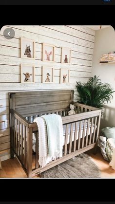 a baby's crib in the corner of a room with pictures on the wall