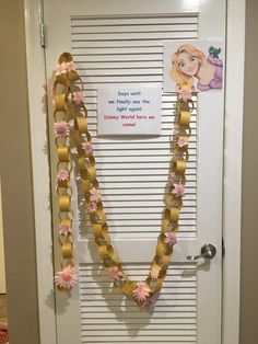 a door decorated with gold ribbon and pink flowers, which is attached to a white door