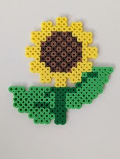 a flower made out of legos sitting on top of a white table next to a black and yellow object