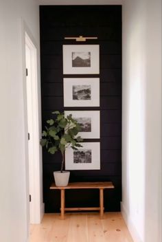 a hallway with black walls and pictures on the wall, a wooden bench in front of it