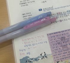 a pen sitting on top of an open book with writing in english and korean characters