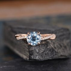 an engagement ring with a blue topazte surrounded by white diamonds on a rock