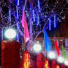 the lights are on and there is a tree in front of it with red, white and blue flags hanging from it