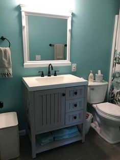 a white toilet sitting next to a sink in a bathroom under a mirror above a vanity