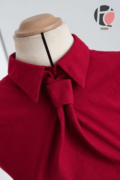 a red shirt with a bow on the neck and collar is being displayed in front of a mannequin's head