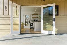 an open door leading into a kitchen and living room area with stools on the floor