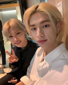 two young men sitting next to each other in front of a mirror with one pointing at the camera