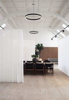 a dining room with white curtains and wooden floors