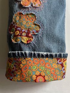 an old pair of jeans has been decorated with colorful flowers and butterflies on it's side