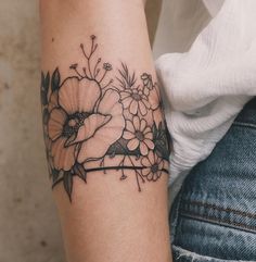 a woman's arm with flowers on it and a black line work tattoo design