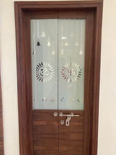 a wooden door with two glass panels and bells on the doors side by side, in front of a white wall