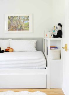 a white bed sitting in a bedroom next to a book shelf with stuffed animals on it