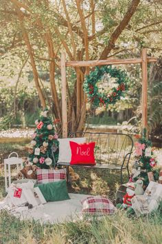 an outdoor setting with christmas decorations and presents on the ground in front of a wooden arbor