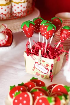 some strawberries are on sticks in a cupcake box with red bows and green leaves