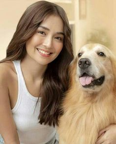 a woman sitting next to a dog on top of a bed