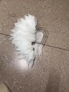 a white feather on the ground next to a pair of shoes