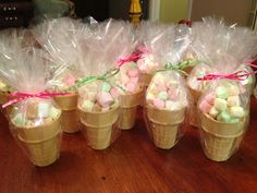 four ice cream cones filled with marshmallows on top of a wooden table